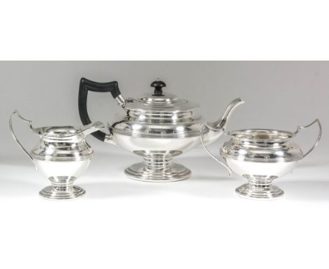 A George V silver three-piece tea service with squat circular bodies, reeded central girdle and moulded footrim, comprising -