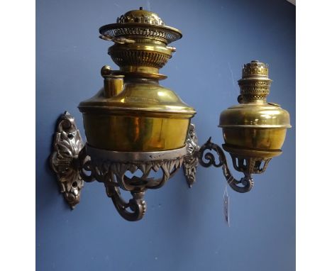 Pair of Victorian ornate wrought iron oil lamp wall sconces, with two brass oil lamps and funnels, one with replacement brass
