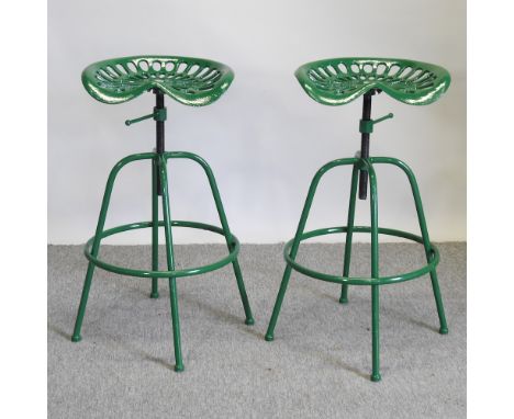 A pair of green painted metal revolving tractor seat bar stools