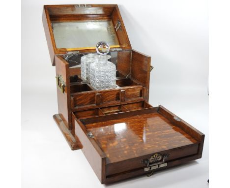 An Edwardian light oak and brass mounted decanter box, with a hinged front and fitted mirrored interior, containing one decan