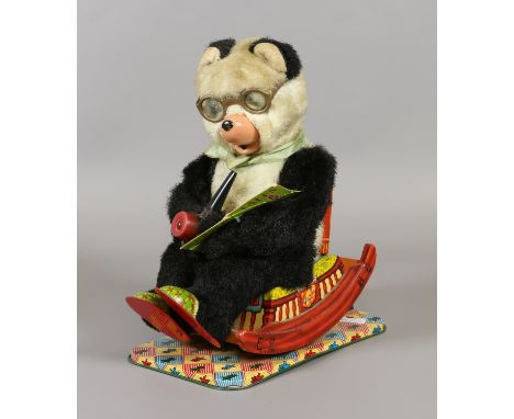 A vintage Japanese RVT tin plate battery operated toy. Formed as a panda reading a book and smoking a pipe seated in a rockin