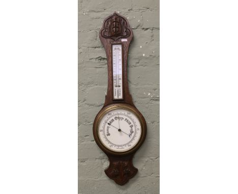 A banjo barometer in carved oak case with opaque glass dials.