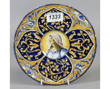 A C19th Faince dish painted with a portrait of the Madonna with stylized border on a blue ground 