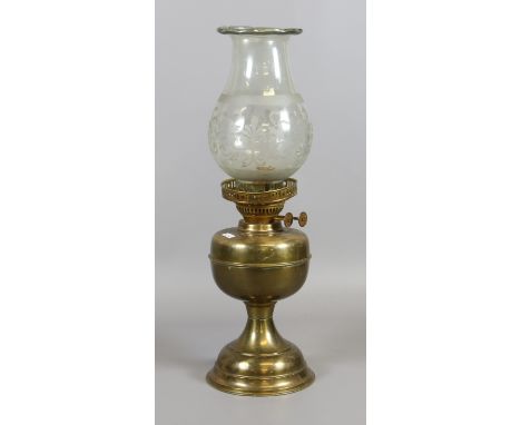 A brass based oil lamp with etched glass shade.
