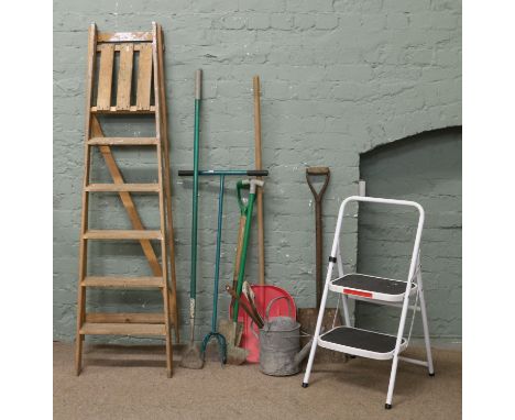 A collection of gardening tools and a two pairs of step ladders.