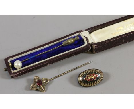 A cased stick pin set with a pearl along with a similar ruby set stick pin and brooch.