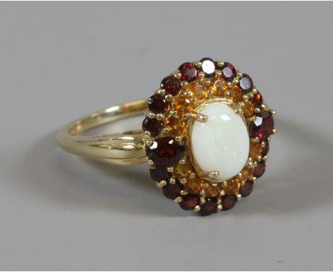 A 9 carat gold ring set with an oval panel of garnets and an opal. Size P.