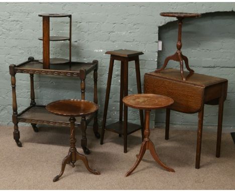 A collection of dark oak and mahogany furniture; two tier tea trolley, plant stand, drop leaf occasional table and three trip