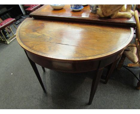 A 19th Century demi-lune card table, the rosewood top with crossbanding and stringing over a mahogany frieze. Top split. 71cm