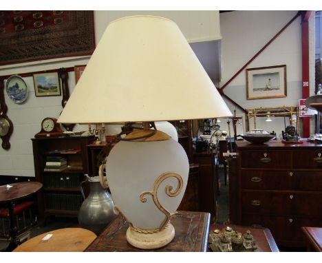 An opaque glass table lamp in scrolled frame