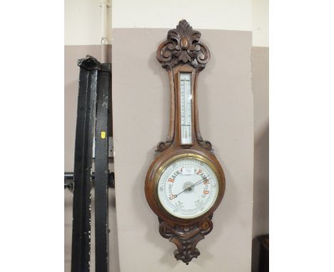 AN EDWARDIAN OAK CARVED ANEROID BAROMETER