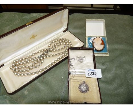 A boxed three strand pearl necklace, a silver hallmarked cameo brooch and a silver three piece locket and chain.