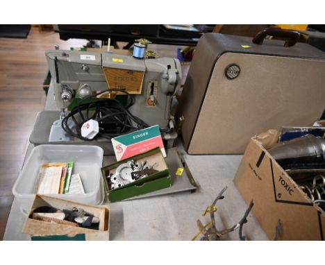 A vintage electric Singer sewing machine and plastic tub of accessories 