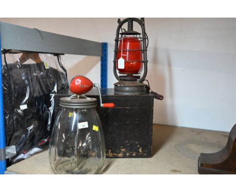 A metal storm lantern with red glass shade, a vintage Blow butter churn and a painted wooden storage box 