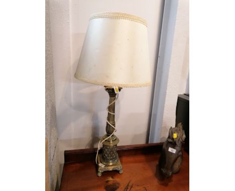 A decorative metal table lamp with cream shade and raised on paw feet 