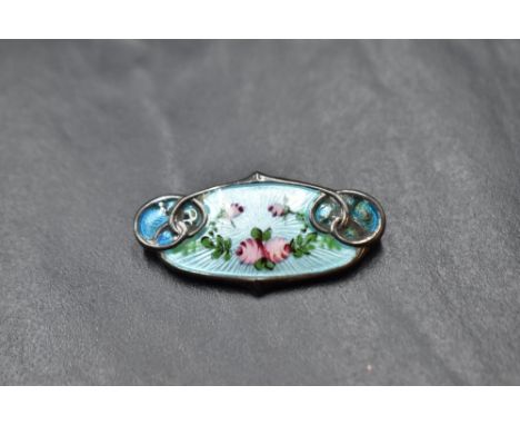 A white metal and enamel brooch stamped sterling having floral decoration