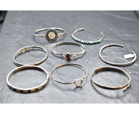 Eight silver bangles of various forms including Egyptian serpent, Mexican Aztec, Rennie Macintosh style etc
