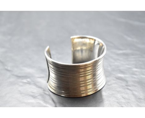 A large silver cuff bangle having linear decoration, approx 100g &amp; 43mm wide