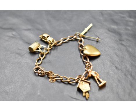 A 9ct gold charm bracelet having six yellow metal charms including two 18ct gold (skis &amp; cuckoo clock), approx 26.5g gros
