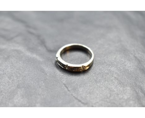 A 14k white metal and diamond set ring, having a linear arrangement of pressure-set diamond baguettes and brilliants totallin
