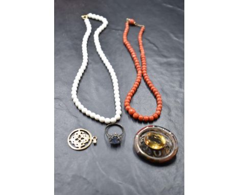 A short string of facet cut coral beads, a silver dress ring, a Celtic white metal oval brooch having a multi agate border an