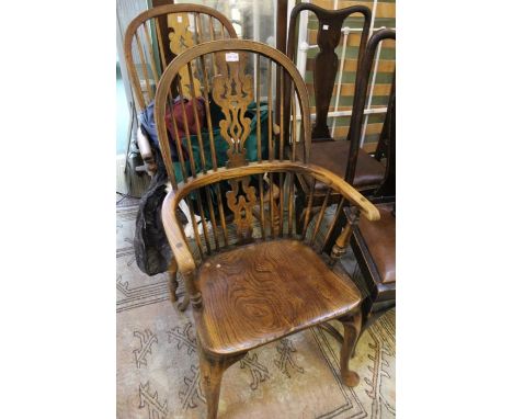 A reproduction elm double comb-back armchair with well figured solid seat, cabriole forelegs united by a crinoline stretcher,