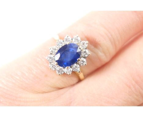 Sapphire and diamond cluster ring, the central oval sapphire measuring approx. 8mm x 6mm, surrounded by twelve small brillian