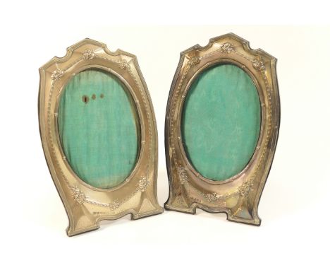 Pair of George V silver photograph frames, Birmingham 1921, shaped oval form bordered with bellflower trails and floral spray