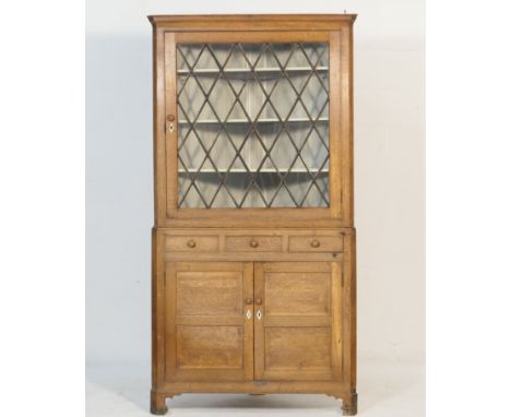 Oak freestanding corner display cabinet, circa 1830, the top having a single lozenge glazed door opening to shelves, over a b