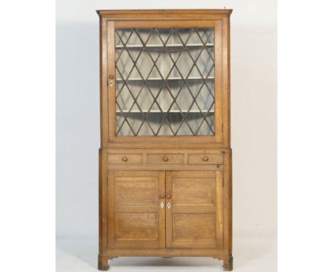 Oak freestanding corner display cabinet, circa 1830, the top having a single lozenge glazed door opening to shelves, over a b