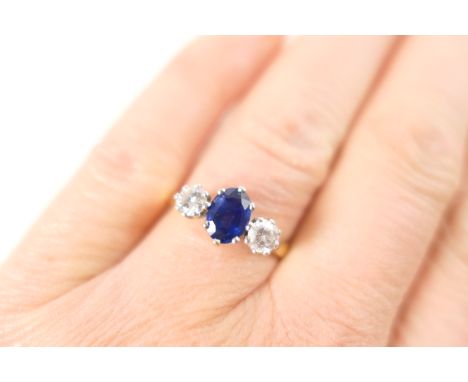 Sapphire and diamond three stone ring, the central oval cut sapphire of approx. 0.70ct, flanked by two brilliant cut diamonds