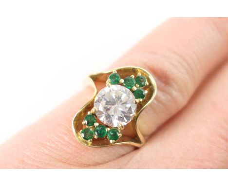 Emerald and cubic zirconia cluster ring, the central brilliant cut white stone bordered with small round cut emeralds in an o