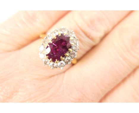 Ruby and diamond cluster ring, the oval cut ruby of approx. 1.5cts, measuring 11mm x 6mm, in yellow gold claw mount, bordered