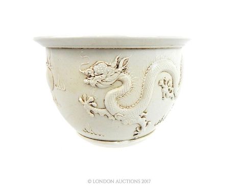 A Chinese Blanc de Chine porcelain jardiniere, decorated with dragons chasing a flaming pearl in relief, 11 x 16 x 16cm.