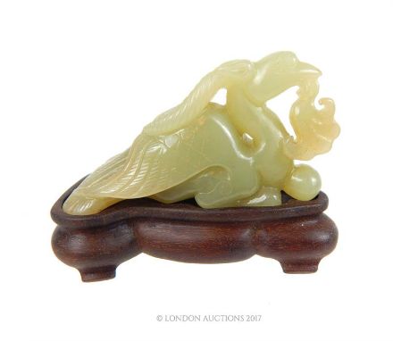 A Chinese jade carving of a Phoenix raised on a wooden stand, 8 x 10 x 6cm.