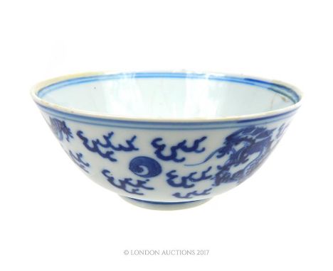 An early 20th century, Chinese, blue and white hand-painted porcelain rice bowl, painted with writhing dragons chasing the pe