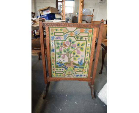 A 1930s wooden and tapestry firescreen 'East or West + Hames Best'. 83cm tall. 
