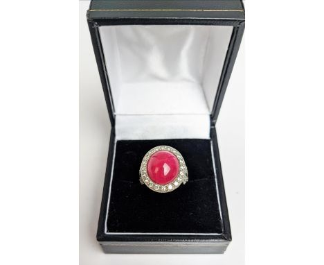 A RUBY AND DIAMOND DRESS RING, white metal shank, the central ruby cabochon of approx 10 carats, size K, 7.16 grams, with box