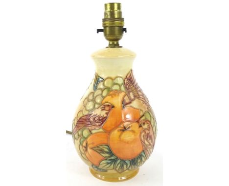 A Moorcroft lamp base, decorated with birds amongst fruit on a peach ground, impressed marks to underside, 20cm H.