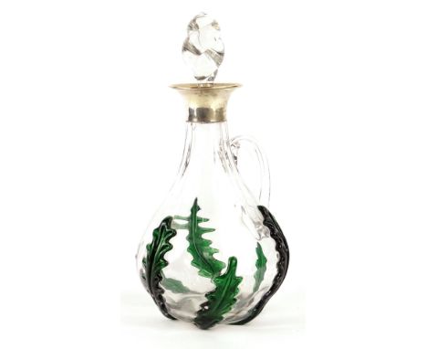 A George V glass decanter and stopper, decorated with stylised green holly type leaves, spirally twisted stopper and silver c