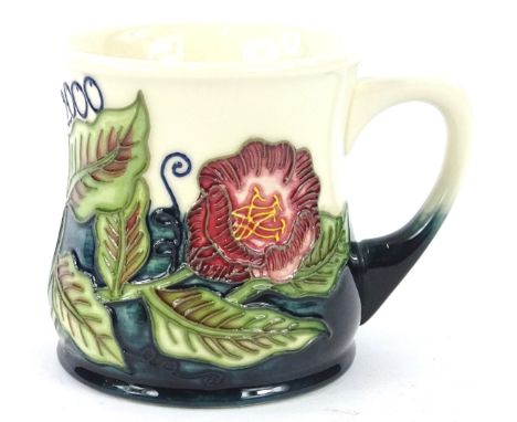 A Moorcroft flower design mug, decorated with flowers, leaves and the date 2000, designed by Marie Penkethman, handwritten to