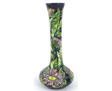 A Moorcroft Aster pattern vase, decorated with flowers and leaves on a dark blue ground, designed and painted by Debbie Hanco