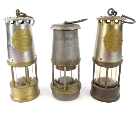 Three miner's lamps, each with a chrome and brass case, to include two Protectors style and another stamped Safety Lamp Compa
