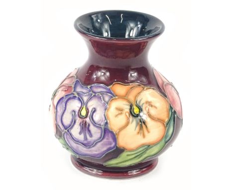 A Moorcroft pottery small vase, with tube lined decoration of a band of pansies on a puce coloured ground, impressed marks to