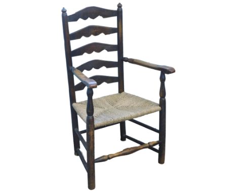 A 19thC oak ladder back elbow chair, with a rush seat on turned supports.