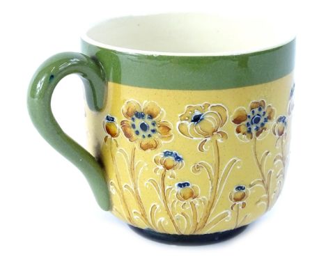 A Macintyre Moorcroft pottery cup, decorated with a design of poppies on a brown ground, with a green handle and border, the 