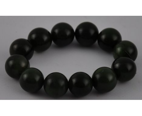 A Chinese bangle of uniform spinach jade beads