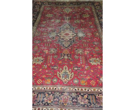 A Tabriz burgandy ground carpet woven with a central floral medallion within a trailing floral field and wide multi border, 3