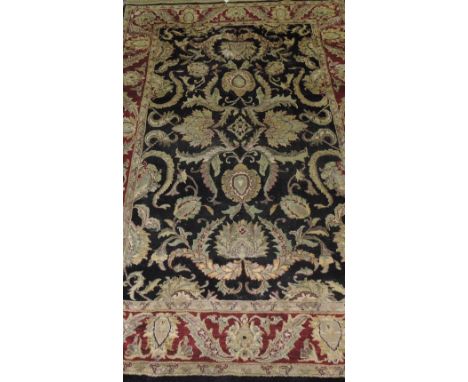 A Tabriz style black ground carpet woven with stylized flower heads within a wide conforming border, 300 x 180cm