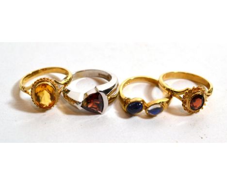 A 9 carat white gold garnet set ring, finger size L; a 9 carat gold moonstone and sapphire ring, finger size M; and two 9 car